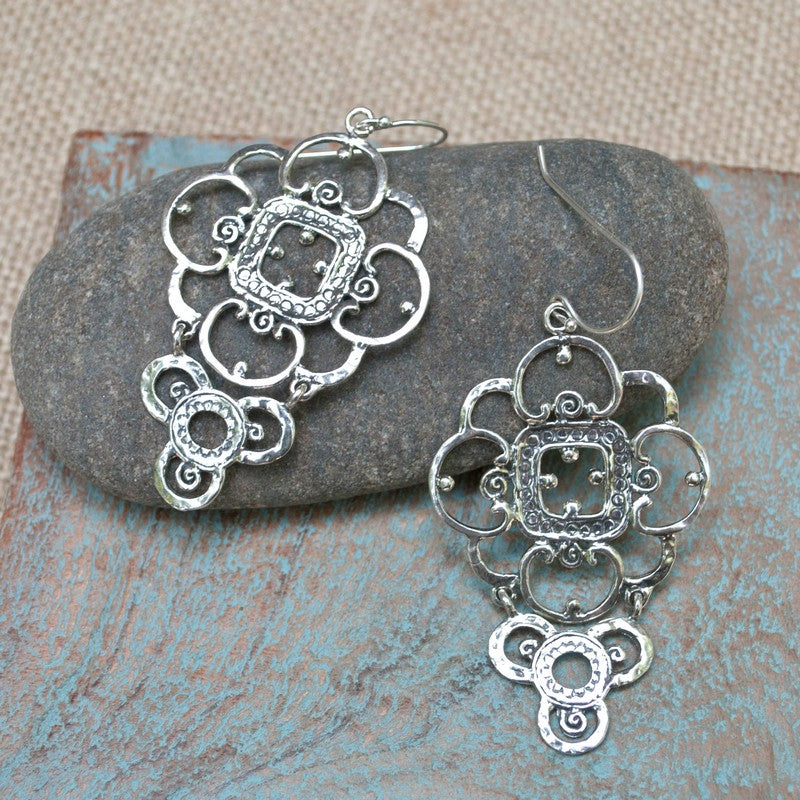 Silver lace earrings are shown on a rock. Delicate details in a bold earring, they measure 2 1/2" long.